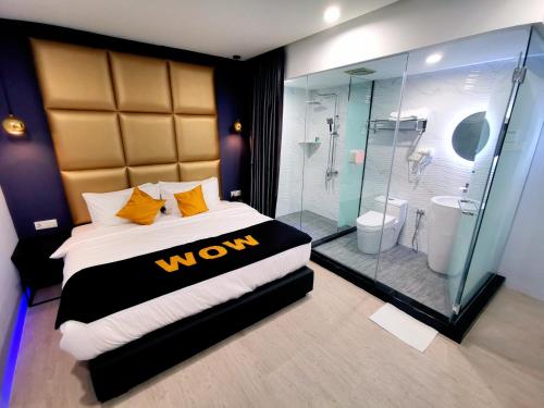 a bedroom with a large bed and a glass shower at WOW Hotel Penang in George Town