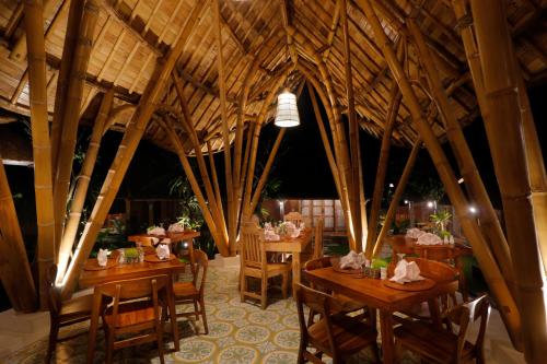 een restaurant met houten tafels en stoelen in een kamer bij De Umah Bali Eco Tradi Home in Bangli