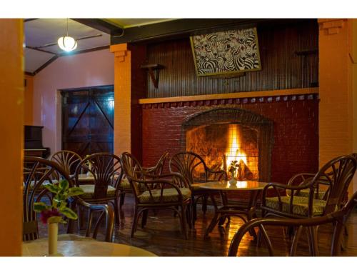 a restaurant with tables and chairs and a fireplace at Thomsons Falls Lodge in Nyahururu