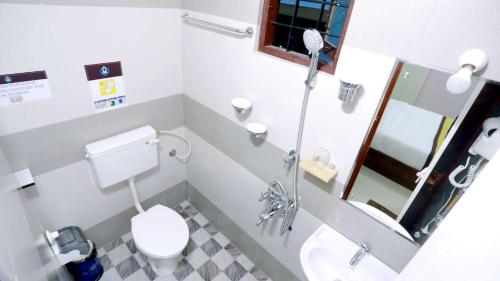 a small bathroom with a toilet and a mirror at Base9 Cochin Airport Hotel in Nedumbassery
