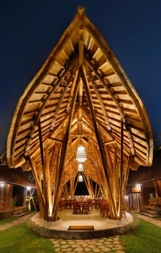 a large wooden building with tables and chairs at De Umah Bali Eco Tradi Home in Bangli