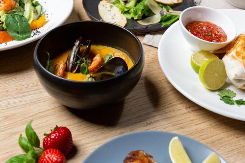 a table with a bowl of soup and plates of food at Corner Hotel in Vilnius