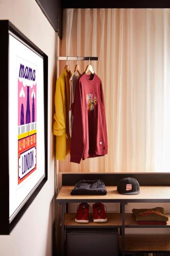 a room with a shelf with jerseys and shoes at Mama Shelter London - Shoreditch in London