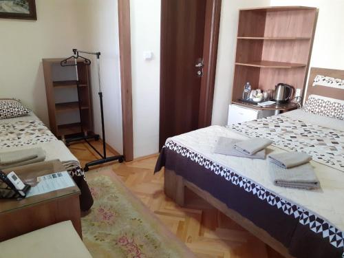 a room with two beds and a table and a shelf at Villa Domina in Gevgelija
