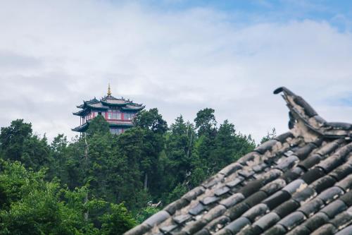 a building in the middle of trees behind a roof at Eden Court in Lijiang