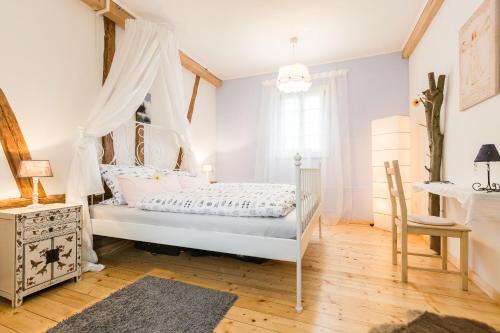 a white bedroom with a canopy bed and a desk at Gemütliche Fachwerkwohnung in Alfter