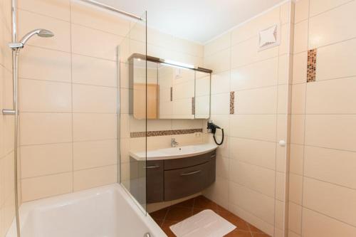 een badkamer met een bad, een wastafel en een douche bij Appartment Hotel Mitterer in Saalbach Hinterglemm