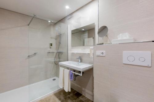 uma casa de banho branca com um lavatório e um chuveiro em Aldiana Club Andalusien em Chiclana de la Frontera