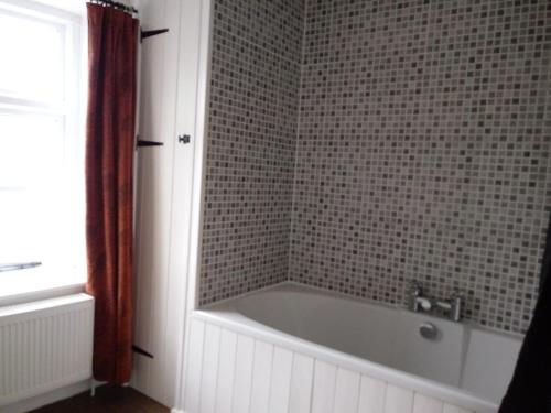 een badkamer met een bad en een betegelde muur bij The Boat Inn in Monmouth