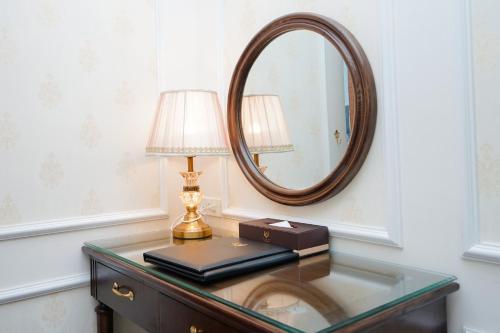 a glass table with a lamp and a mirror at Vincent Halong Hotel in Ha Long