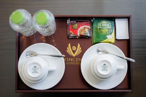 a tray with two plates and two spoons and glasses at Vincent Halong Hotel in Ha Long