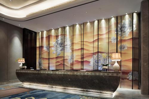 a lobby with a wall mural of trees at Wanda Vista Hotel Urumqi in Ürümqi