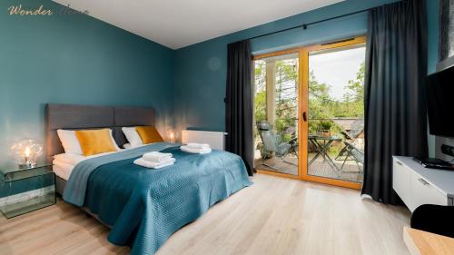 Dormitorio azul con cama y puerta corredera de cristal en Wonder Home - Apartamenty z widokami i blisko szlaków - w spokojnej części Karpacza, en Karpacz