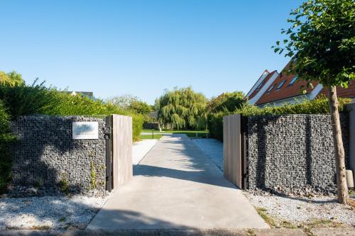 a gate in a stone wall with a sidewalk at Villa Farfalla in Bredene