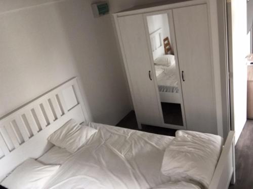 a bedroom with a white bed and a mirror at Camping Thalassa Belgische Kust Vakantiehuis in Bredene