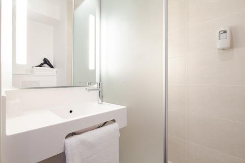 La salle de bains blanche est pourvue d'un lavabo et d'un miroir. dans l'établissement B&B HOTEL Igny Palaiseau, à Igny