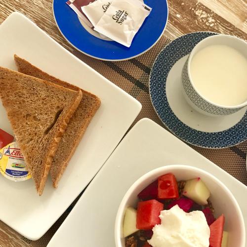 a plate with toast and a bowl of fruit and a cup of coffee at Villa Argia Nusa Penida in Nusa Penida