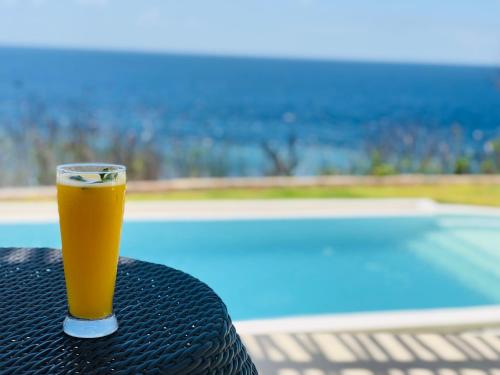 un vaso de cerveza sentado en una mesa junto a una piscina en Villa Argia Nusa Penida en Nusa Penida