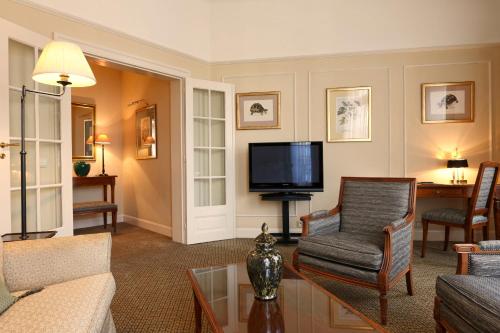 a living room with a couch and a tv at Hotel Le Plaza Brussels in Brussels