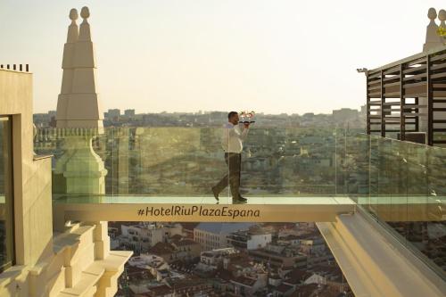 a man taking a picture of a city from the top of a building at Riu Plaza España in Madrid