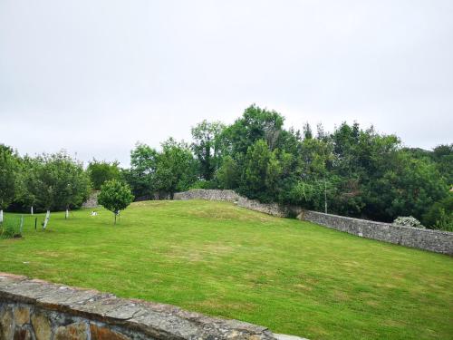 a large grassy field next to a stone wall at Apartamentos La Tarazana 2 in La Pereda de Llanes
