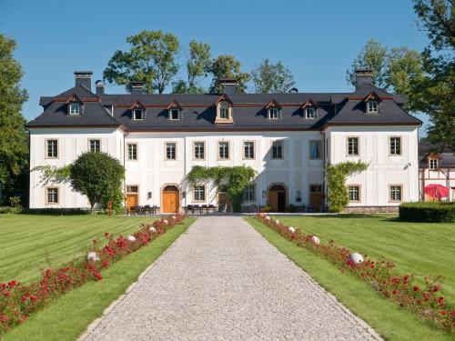 une grande maison blanche avec une allée. dans l'établissement Pałac Pakoszów Schlosshotel Wernersdorf, à Jelenia Góra