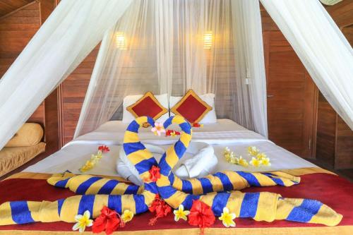 ein Bett mit einer Decke und Kissen darauf in der Unterkunft Lembongan Mantra Huts - CHSE Certified in Nusa Lembongan