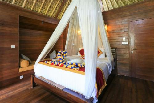 a bedroom with a bed with a mosquito net at Lembongan Mantra Huts - CHSE Certified in Nusa Lembongan