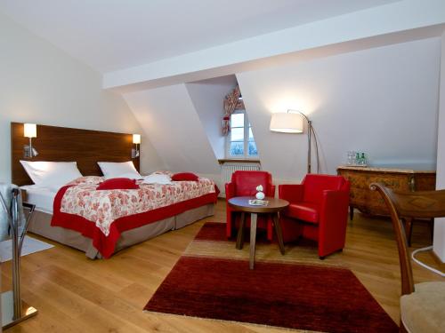 a bedroom with a bed and a red chair at Pałac Pakoszów Schlosshotel Wernersdorf in Jelenia Góra