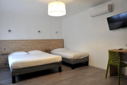 a room with two beds and a flat screen tv at Grand Hôtel in Sainte-Foy-la-Grande