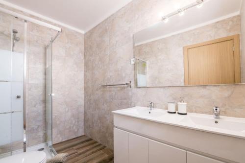 a bathroom with a sink and a shower and a mirror at LovelyStay - Sweet Escape II - Backyard in Quarteira