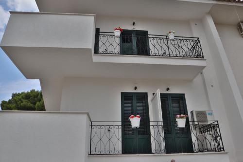 a white building with green doors and flowers on the balconies at Fiore di Loto Rooms in Carini