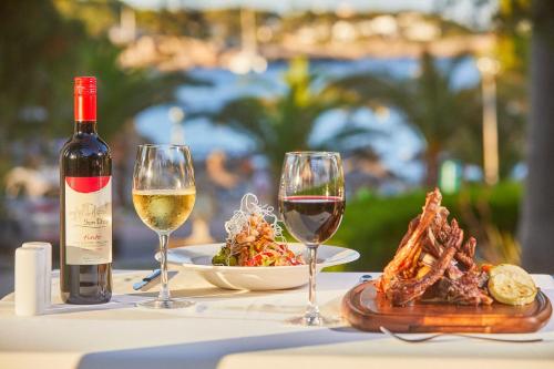a table with two glasses of wine and a plate of food at Hotel Rocamarina - Adults Only in Cala d´Or