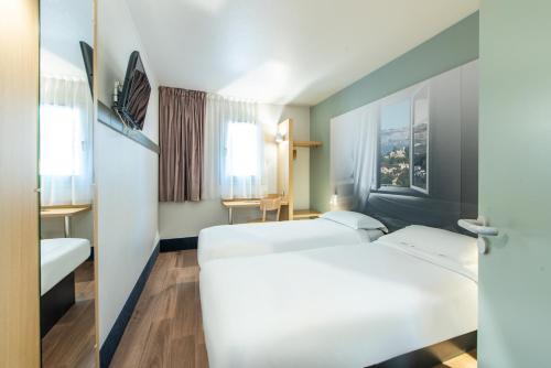 una camera d'albergo con due letti e una finestra di B&B HOTEL Antibes Sophia Le Relais a Biot