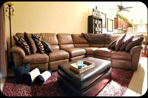 ein Wohnzimmer mit einem braunen Ledersofa in der Unterkunft A Private Bedroom in Orlando