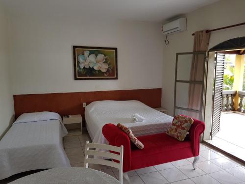 1 dormitorio con 2 camas y banco rojo en Esplanada Hotel, en Paraguaçu Paulista