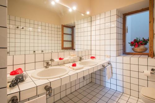 a white tiled bathroom with two sinks and a window at Casamariuccia in Massino Visconti