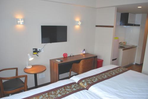 Schlafzimmer mit einem Bett, einem Schreibtisch und einem TV in der Unterkunft Ten Point Hotel Airport in Naha