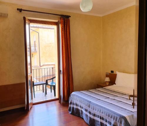 um quarto com uma cama e uma porta para uma varanda em Albergo Leon d'Oro em Castel San Giovanni