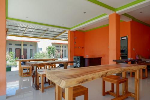 a room with tables and chairs and orange walls at RedDoorz near Taman Makam Pahlawan Tatura in Palu
