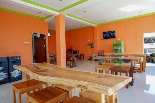 a room with tables and chairs and orange walls at RedDoorz near Taman Makam Pahlawan Tatura in Palu