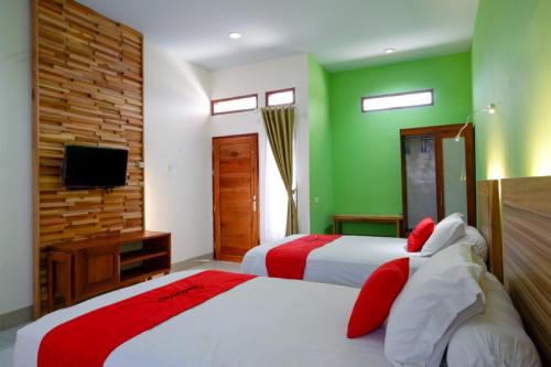 a bedroom with two beds with green walls and a tv at RedDoorz near Taman Makam Pahlawan Tatura in Palu