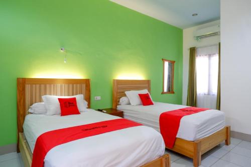 two beds in a room with green walls at RedDoorz near Taman Makam Pahlawan Tatura in Palu