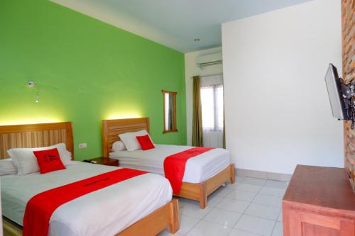 two beds in a room with green walls at RedDoorz near Taman Makam Pahlawan Tatura in Palu