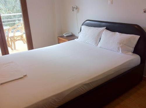 Cama blanca con cabecero negro en una habitación en Hotel Magnolia, en Loutra Edipsou