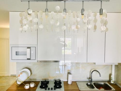 una cocina con armarios blancos y una lámpara de araña en 4-room jacuzzi apartment, en Leópolis