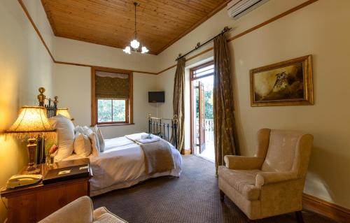 ein Schlafzimmer mit einem Bett, einem Stuhl und einem Fenster in der Unterkunft Evergreen Manor and Spa in Stellenbosch