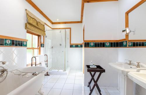 uma casa de banho com 2 lavatórios, uma banheira e um chuveiro em Evergreen Manor and Spa em Stellenbosch