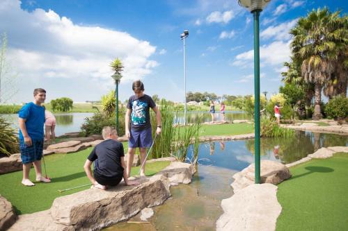 a group of people standing on a putting green near a pond at Umuzi Lodge in Secunda