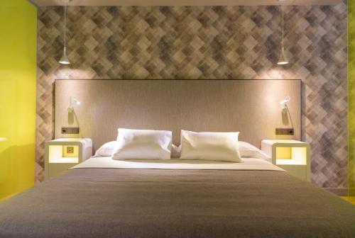 a bedroom with a large bed with two night stands at Hotel Macià Sevilla Kubb in Seville